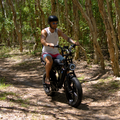 Fat tyre electric bike with dual battery system riding through a forest trail demonstrating off road performance.